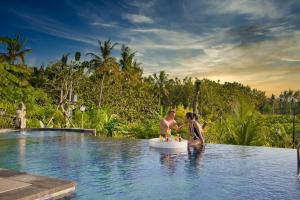 a man and woman sitting in a swimming pool at NG Sweet Home in Nusa Penida