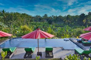 an outdoor pool with chairs and an umbrella at NG Sweet Home in Nusa Penida