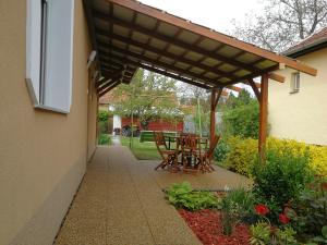 a patio with a wooden pergola and a table and chairs at Ágnes Vendégház in Gyula