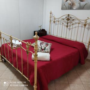 a metal bed with a red blanket and a pillow at Baglio Cracchiolo da Tuzzo - Casa Il Limone in San Vito lo Capo