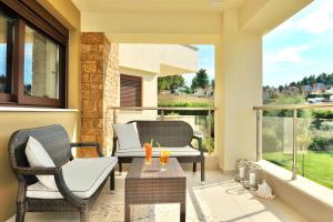 a patio with two chairs and a table on a balcony at Sani Polyastron Hotel & Spa in Sani Beach