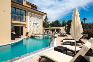 a swimming pool with lounge chairs and an umbrella at Dna Hotel Dalyan in Dalyan