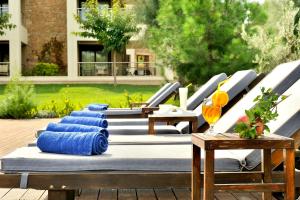 a row of lounge chairs with blue pillows on them at Sani Polyastron Hotel & Spa in Sani Beach