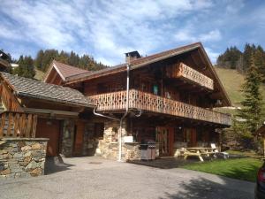 a large wooden cabin with a balcony and a table at Chalet 13 personnes-Le Vanvolet in Les Saisies