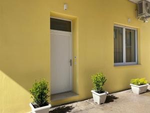 a yellow house with two potted plants in front of a door at Sogni di Sabbia in Porto Potenza Picena