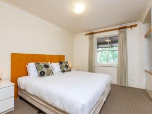 Un dormitorio con una gran cama blanca y una ventana en Villa 2br Riesling Villa located within Cypress Lakes Resort, en Pokolbin