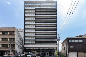 un edificio alto con coches estacionados frente a él en 谷町君ホテル　難波80 en Osaka
