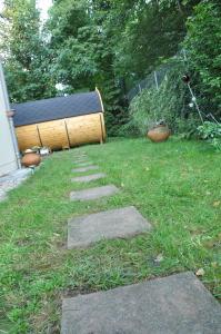 einen Garten mit einer Holzbank im Gras in der Unterkunft Holz-Wohnfass in München-Nymphenburg in München