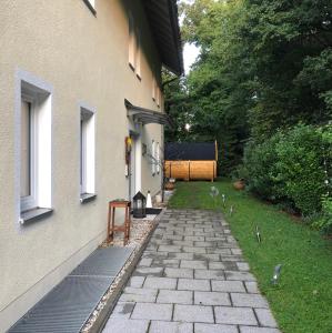einen Steinweg neben einem Gebäude mit einer Bank in der Unterkunft Holz-Wohnfass in München-Nymphenburg in München