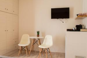 a room with three white chairs and a table and a tv at Langhi Apartments 2 in Missolonghi