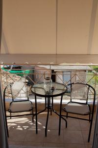 a glass table and chairs on a balcony at Langhi Apartments 2 in Mesolongion