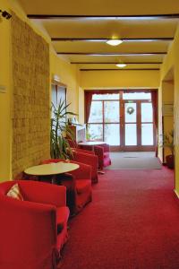 a waiting room with red chairs and a table at Hotel Harrachov Inn in Harrachov