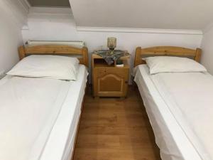 two beds in a room with a side table at Engi Panzió in Ocna de Sus +55 photos