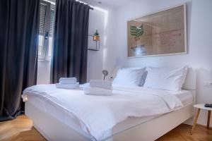 ein weißes Bett mit weißer Bettwäsche und Kissen darauf in der Unterkunft Vanni apartment in Zadar