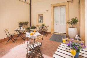 un patio con mesas y sillas en una habitación en Dimore delle Zagare Ortigia en Siracusa