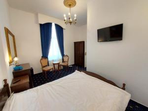 a bedroom with a bed and a table and chairs at Weiss Little Palace in Braşov +31 photos