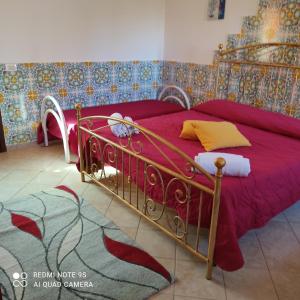 um quarto com uma cama com uma colcha vermelha em Baglio Cracchiolo da Tuzzo - Casa Fico D'India em San Vito lo Capo