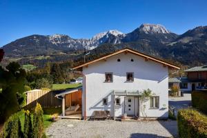 ein weißes Haus mit Bergen im Hintergrund in der Unterkunft Ferienhaus Kaffeesatz in Schönau am Königssee