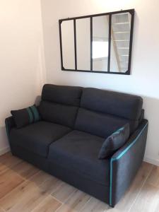 a black couch in a living room with a mirror at Entre Terre et Mer in La Méaugon
