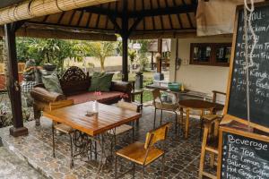 un patio con mesas, sillas y una pizarra en Ubud Shanti Rice Field House By Supala en Ubud