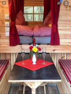 a table with two glasses and a vase with flowers on it at Holz-Wohnfass in München-Nymphenburg in Munich