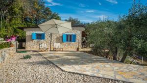 a stone house with a patio and an umbrella at Holiday Home Casa Oliva II in Nerezine