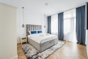 ein Schlafzimmer mit einem großen Bett und blauen Vorhängen in der Unterkunft Rya Residence Oradea in Oradea