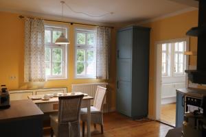 eine Küche mit einem Tisch, Stühlen und Fenstern in der Unterkunft Forsthaus in Waldhessen in Bauhaus