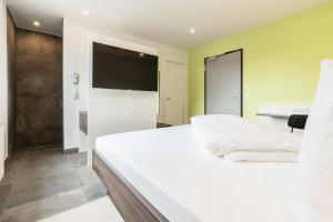 a bedroom with a large white bed and a bathroom at a2 HOTELS Wernau am Quadrium in Wernau