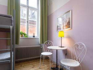 
a room with a table, chairs and a lamp at Castanea Old Town Hostel in Stockholm
