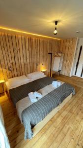 a large bed in a room with wooden walls at RamsAu-das Gasthaus in Bad Heilbrunn