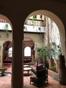 um arco com um banco num pátio com plantas em Ryad Bahia em Meknès