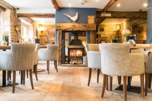 comedor con chimenea, mesas y sillas en The Pickled Pheasant en Holmfirth