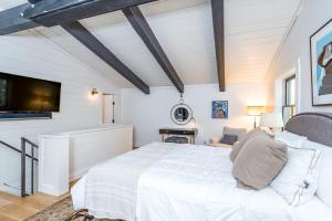 a white bedroom with a large bed and a tv at Deer Park - Ski Ranches in Telluride