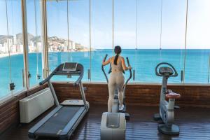 Kobieta na bieżni w siłowni patrząca na ocean w obiekcie Hotel Boutique Villa Venecia w mieście Benidorm