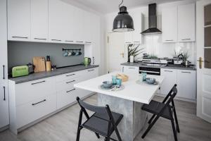 a kitchen with white cabinets and a white table and chairs at Apartament Monopoli in Ustka
