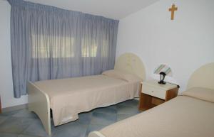 een kamer met 2 bedden en een kruis op een raam bij Residence Fontana Barone in Cefalù