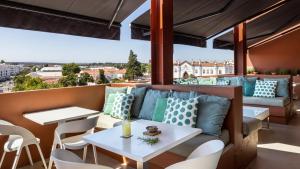 een patio met een bank, tafels en stoelen bij Vitoria Stone Hotel in Évora