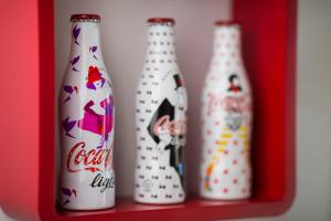 Coca gare في كليرمون فيران: مجموعة من اربع زجاجات جالسين على رف احمر
