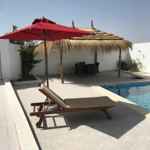 a chair with an umbrella next to a swimming pool at Maison dhiefa avec piscine in Temlale