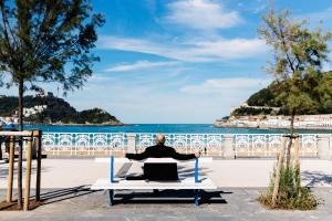 un hombre sentado en una mesa de picnic frente a la playa en BARTOLOME Suite Apartment, en San Sebastián