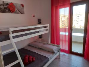 een slaapkamer met een stapelbed en een raam met rode gordijnen bij Shardana in Quartu SantʼElena