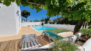 ein Pool mit zwei Bänken, einem Tisch und einem Baum in der Unterkunft Villa Gabriel by Sunny Deluxe in Albufeira