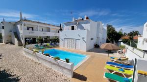 ein weißes Haus mit einem Pool und Stühlen in der Unterkunft Villa Gabriel by Sunny Deluxe in Albufeira