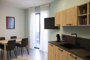 una cucina con tavolo e sedie e una cucina con lavandino di Bloom Apartments a Trento