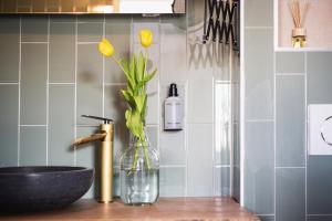a bathroom with a sink and a vase with yellow flowers at Boutique Hotel Enkhuizen in Enkhuizen