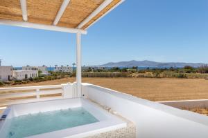 uma banheira numa varanda com vista para um campo em Villa Gold & White em Maragkas