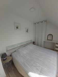 Un dormitorio blanco con una cama grande y una mesa en Gites Le John Jeffries - Le Grand Jeff, en Guînes