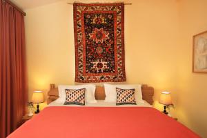 Silk Road Hotel في يريفان: غرفة نوم بسرير احمر ومخدات وسجادة على الحائط