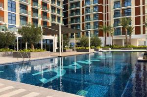 a large swimming pool in front of a building at Calm Studio in Damac Celestia A Dubai South by Deluxe Holiday Homes in Dubai